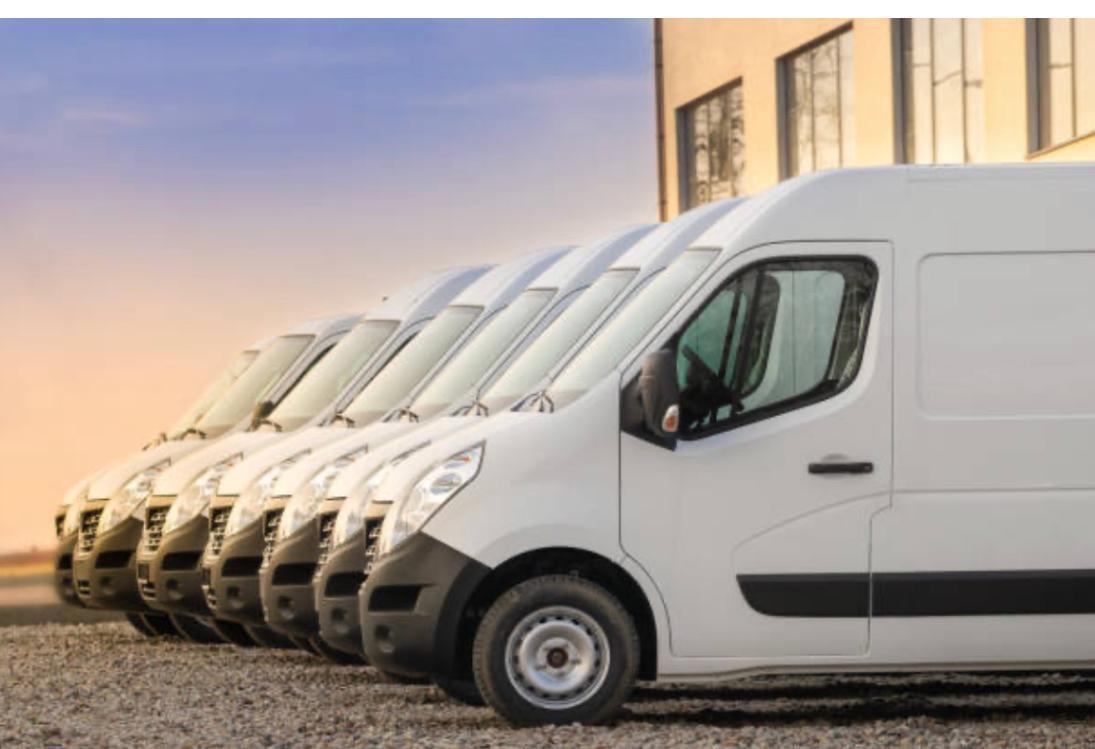 Furgonetas blancas de GMalaga en fila al aire libre, mostrando la flota de la empresa.