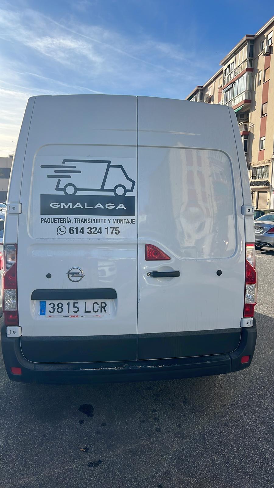 Parte trasera de una furgoneta de GMalaga aparcada en la calle, con la marca y la matrícula visibles.