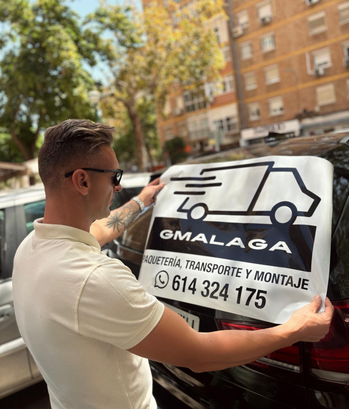 Trabajador colocando el vinilo con el logotipo de GMalaga en la parte trasera de un coche.